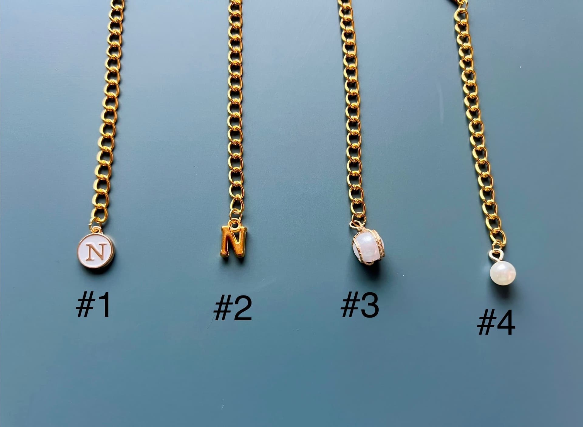 All four charm styles: white initial, gold initial, pearl with gold, and simple pearl