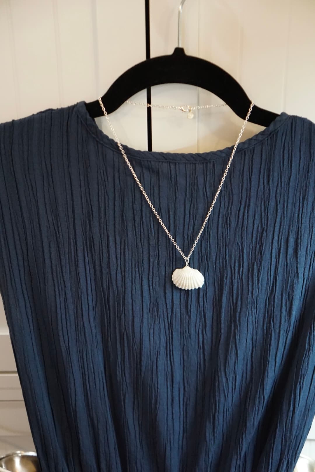 Seashell necklace displayed on blue dress hanger